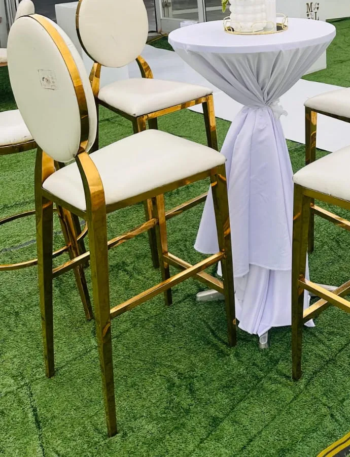 Gold-framed cocktail stools around a white-clothed cocktail table dressed with a floral arrangement